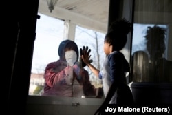 Сотрудник одного из госпиталей в Нью-Йорке общается с дочерью через окно, соблюдая меры социального дистанцирования. 11 апреля