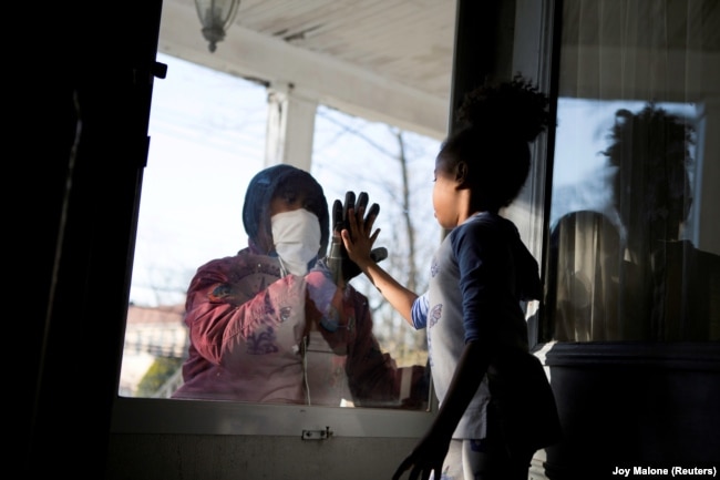 Сотрудник одного из госпиталей в Нью-Йорке общается с дочерью через окно, соблюдая меры социального дистанцирования. 11 апреля