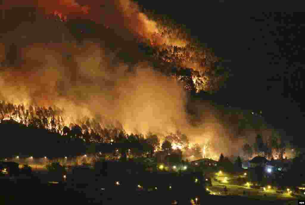 Flames burn trees near houses during a fire earlier this week that damaged woodland near Bilbao in Spain. (epa/Miguel Tona)