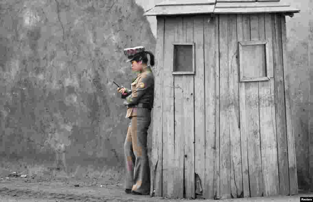 A female North Korean soldier uses her mobile phone next to a sentry on the banks of the Yalu River, near the town of Sinuiju, opposite the Chinese border city of Dandong. (Reuters/Jacky Chen)