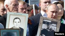 Russian President Vladimir Putin (right) holds a portrait of his father as he takes part in the Immortal Regiment march on Red Square in Moscow in May 2015.