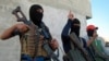 Masked Sunni gunmen pose with their weapons during a patrol outside the city of Falluja.