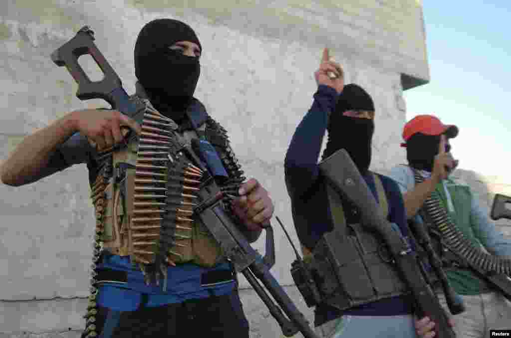 Masked Sunni gunmen pose with their weapons during a patrol outside the city of Falluja.