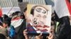 Iraqi Sunni protesters hold up a defaced portrait of Prime Minister Nuri al-Maliki in Ramadi on January 4.