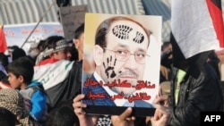 Sunni protesters hold up a defaced portrait of Iraqi Prime Minister Nuri al-Maliki at a rally in Ramadi in January 2013.