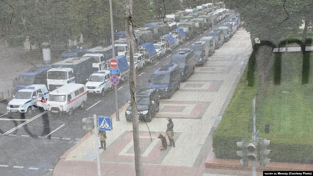 Polizeiautos und Menschen in Militäruniform mit Hunden in der Nähe der Präsidialverwaltung in Minsk, 9. August