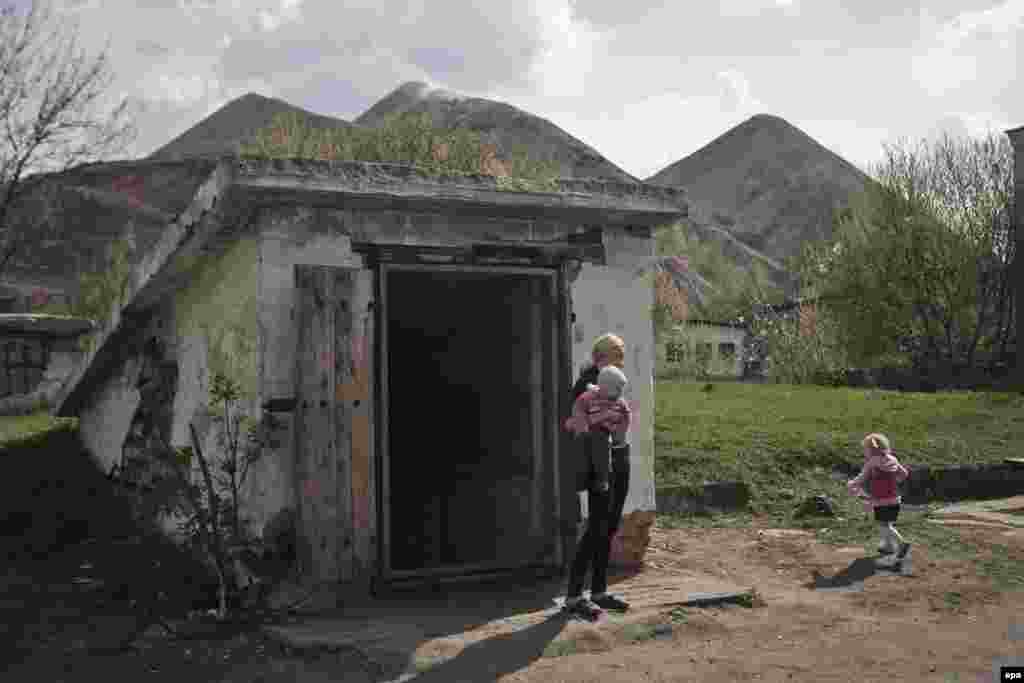 A local woman with children stands outside the entrance to an air-raid shelter near the Chelyuskintsev coal mine in the Petrovsky district of Donetsk, in eastern Ukraine. (epa/Valentin Egorshin)