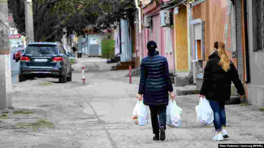 Поодинокі перехожі повертаються з магазину додому