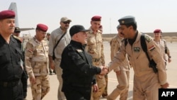 A handout picture released by the Iraqi prime minister's press office on July 9, 2017, shows Iraqi Prime Minister Haider al-Abadi (c) shaking hands with army officers upon his arrival in Mosul.