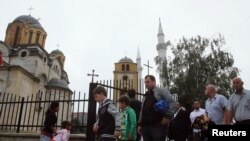 Disa persona duke dalë nga xhami në Ferizaj, e cila gjendet në një oborr me Kishën Ortodokse. Fotografi nga arkivi