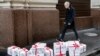 An opposition activist wearing a rubber mask depicting Russian President Vladimir Putin walks past gift boxes reading "Trial," "Resignation," "Impeachment," "True Election," and "Lustration" in Moscow on October 7.