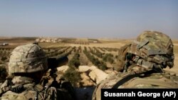 U.S. troops look toward the border with Turkey from a small outpost near the town of Manbij in northern Syria on February 7.