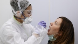 Медична працівниця бере зразок у жінки для перевірки на коронавірусну хворобу