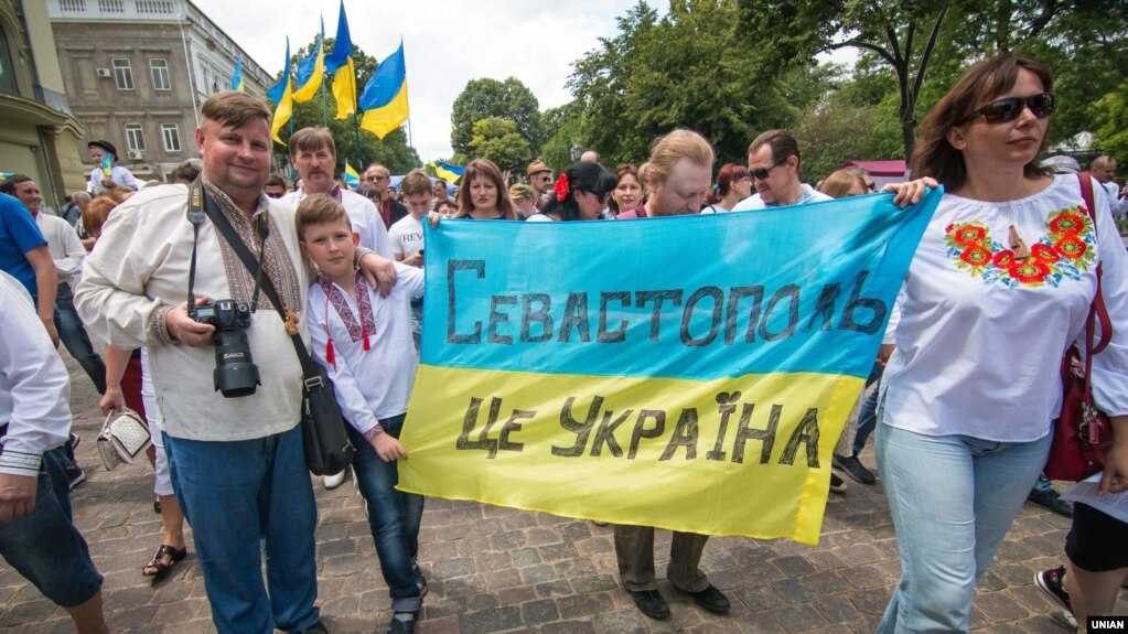Участники марша за территориальную целостность Украины несут ткань в цветах украинского флага с надписью: "Севастополь- это Украина". Одесса, 19 мая 2018 года.