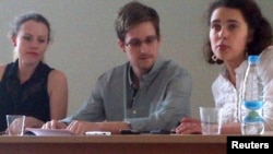 Гражданин США Эдвард Сноуден (в центре), Сара Харрисон (слева) из WikiLeaks общаются с правозащитниками в аэропорту Шереметьево в Москве. 12 июля 2013 года. 