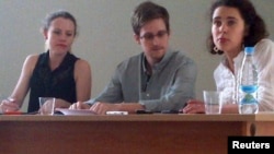 Эдвард Сноуден (ортада) Шереметьево әуежайында Ресейлік және шетелдік құқық қорғаушылармен кездесіп отыр. Мәскеу, 12 шілде 2013 жыл.