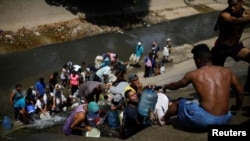 Жители обесточенного Каракаса, где нет и водоснабжения, собирают жидкость из городской сточной канавы