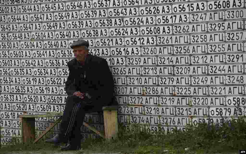 Un om în vîrstă în fața unui zid placat cu numere de mașini în satul Vank, nu departe de Stepanakert, în regiunea separatistă Nagorno-Karabakh. (AFP/Andrei Golovanov)