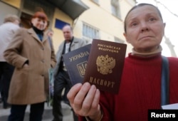 Украина және Ресейден алған екі төлқұжатын көрсетіп тұрған әйел. Қырым, 7 сәуір 2014 жыл.