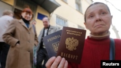 A woman poses with a Ukrainian and a Russian passport outside an office of the Russian Federal Migration Service, where she received a Russian passport, in the Crimean city of Simferopol in April.