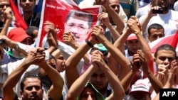 Supporters of the Muslim Brotherhood's presidential candidate Muhammad Morsi hold his portrait during a demonstration on Cairo's Tahrir Square 