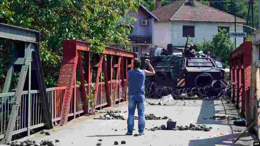 A Kosovo Serb gestures to troops in a German KFOR armored vehicle guarding a bridge in the village of Rudare, near the northern Kosovo town of Zvecan, on June 1. A NATO soldier and three Kosovo Serbs were wounded in clashes that erupted as NATO units moved to dismantle Serb-held barricades in northern Kosovo. (AFP)