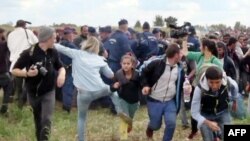 Фрагмент видеозаписи, на которой видеооператор Петра Лазло пинает мигрантов во время инцидента на венгерско-сербской границе, сентябрь 2015 года. 