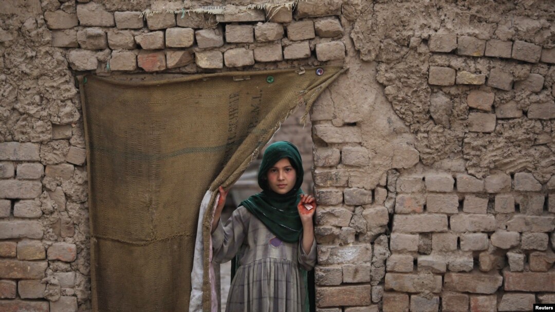A Pashtun girl looks out from the doorway of her family dwelling in Peshawar.