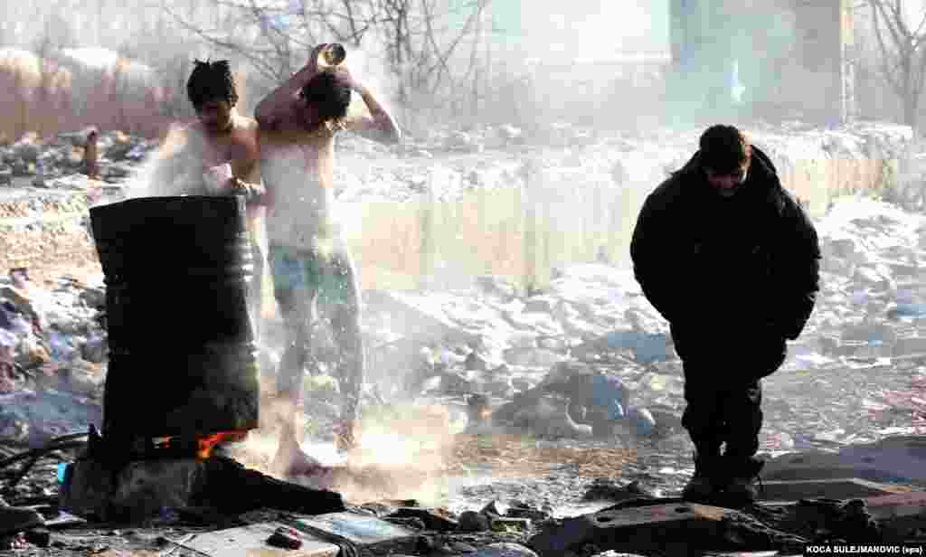 Migrants wash themselves using water from a barrel heated by a fire underneath it at an abandoned customs warehouse in Belgrade. (epa/Koca Sulejmanovic)