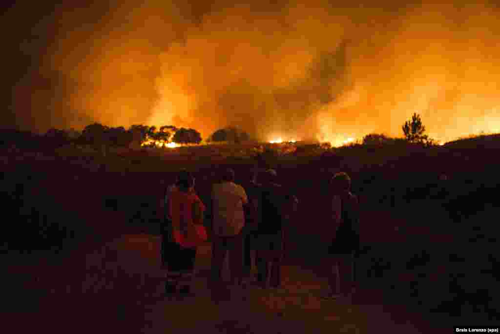 Residents of the village of Vilardevos in northwestern Spain observe a large forest fire that prompted warnings from authorities. (epa/Brais Lorenzo)