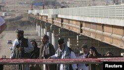 Afghans cross a border bridge over the Pyanj River into the Tajik town of Lower Pyanj, 26Aug2007