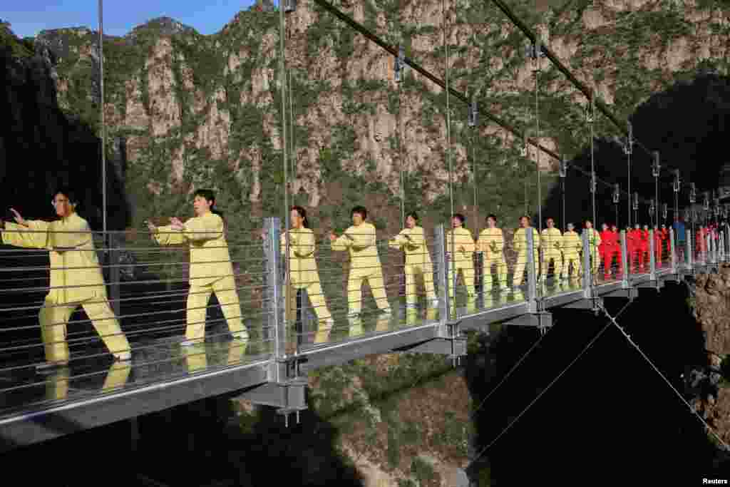 People practice tai chi on a suspension bridge during an event at a tourist spot in Beijing, China. (Reuters)