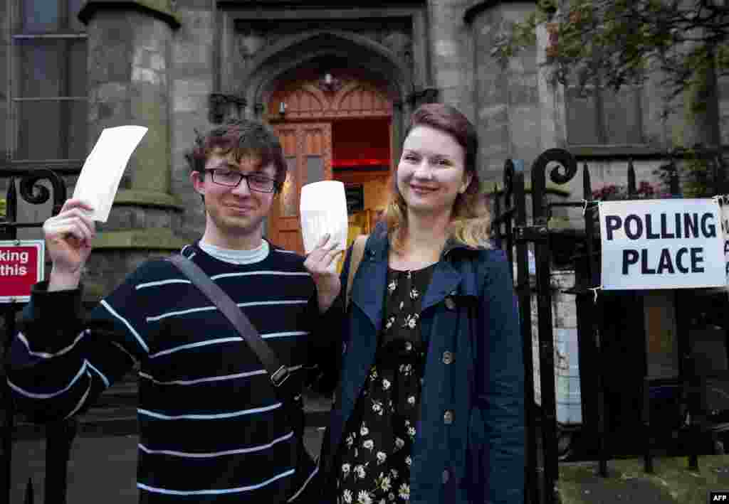 Молодая пара держит в руках бюллетени около участка для голосования под Эдинбургом 