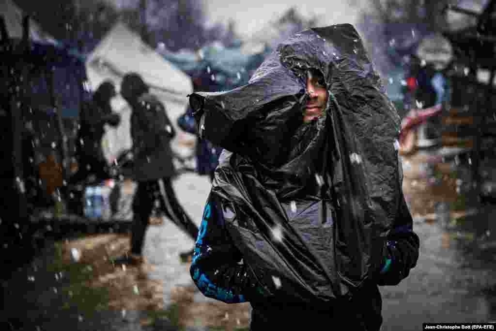 A migrant covers himself with a plastic bag during a rainstorm at the Vucjak refugee camp outside Bihac, Bosnia-Herzegovina. According to local media, hundreds of people remain at the camp even after international officials called for it to be shut down. (epa-EFE/Jean-Christophe Bott)