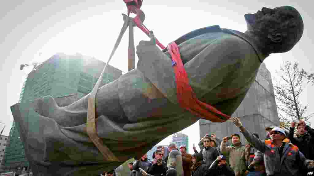 A crowd watches workers take down the last bronze statue of Vladimir Lenin in Ulan Bator, the capital of Mongolia, on October 14 after Mayor Bat-Uul Erdene denounced the communist leader as a &quot;murderer.&quot; For decades, Vladimir Lenin was worshipped by Mongolian schoolchildren as Teacher Lenin. (AFP/Byambasuren Byamba-Ochir)