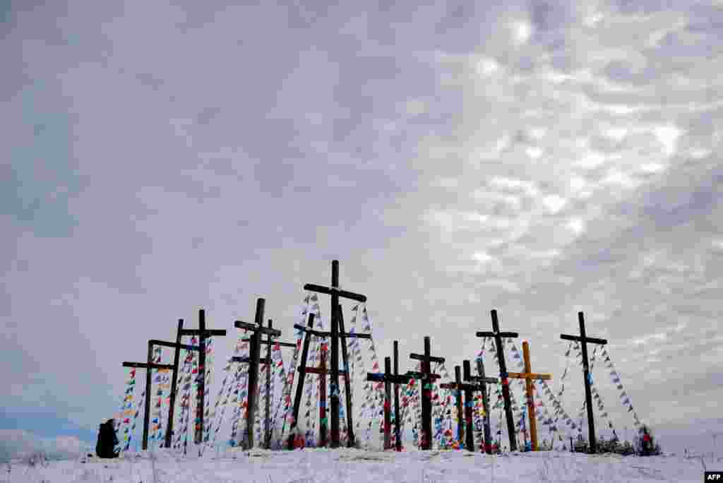 A woman prays on a hill with wooden crosses as she celebrates Palm Sunday in the town of Oshmiany, some 130 kilometers northwest of Minsk, Belarus, on March 20. (AFP/Sergei Gapon)