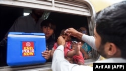 A Pakistani health worker administers polio-vaccine drops to a child at a railway station in Lahore on May 16.
