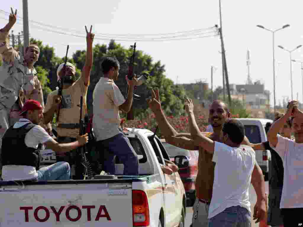 Локалните жители го поздрават напредокот бунтовничките борци во предградието на Триполи на 22 август. 