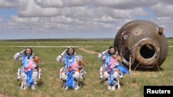 Chinese astronauts salute after returning to earth in the reentry capsule of China's "Shenzhou-10"