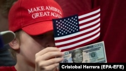 Дитина тримає доларову банкноту 2020 року з зображенням президента США Дональда Трампа