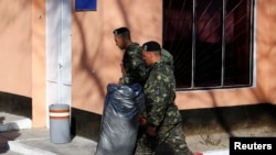 Ukraine -- Ukrainian marines carry personal belongings before departing Crimea, outside a Ukrainian military base in the Crimean port city of Feodosia, March 24, 2014