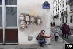 Прохожая делает селфи на фоне портретов погибших журналистов "Шарли Эбдо"