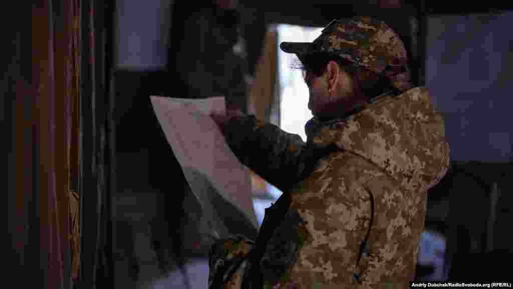 Одна из военнослужащих читает бюллетень с кандидатами в президенты на избирательном участке под Станицей Луганской