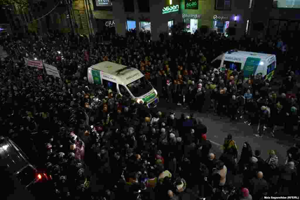 Машина скорой помощи едет через толпы протестующих в Тбилиси.