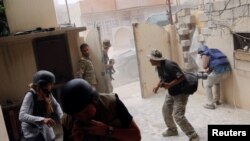 Gazetarët në Irak duke u mbrojtur pas shpërthimit të një makine bombë në luftimet ndërmjet forcave irakiane dhe militantëve të IS-it. 