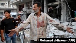 A Syrian man gestures near debris following a reported Russian air strike last month in Idlib Province.