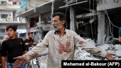 A Syrian man gestures near debris following a reported Russian air strike last month in Idlib Province.