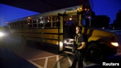 A police officer stands near a school bus used to evacuate attendees of the Muhammad Art Exhibit and Contest sponsored by the American Freedom Defense Initiative after a shooting outside the Curtis Culwell Center where the event was held in Garlan, Texas on May 3.