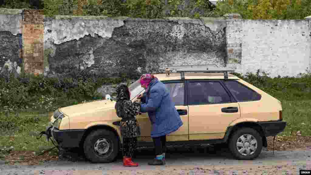 Пожилая женщина с девочкой у машины во время эвакуации&nbsp;