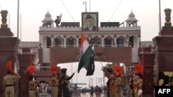 FILE: Pakistani Rangers and Indian Border Security Force personnel lower their respective country flags at the Beating Retreat Ceremony at the India-Pakistan Wagah border post.